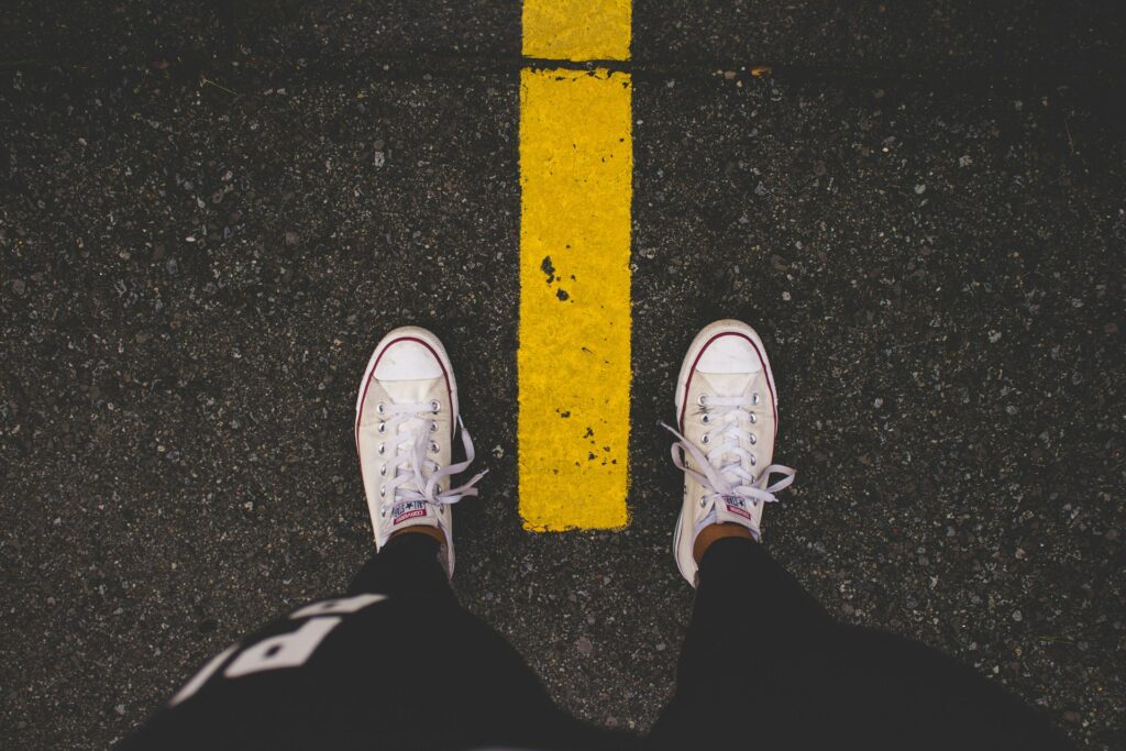 A person standing with a yellow line between their shoes symbolizes setting boundaries